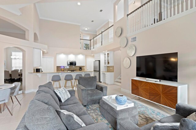 living room featuring crown molding, a chandelier, a high ceiling, and light tile patterned floors