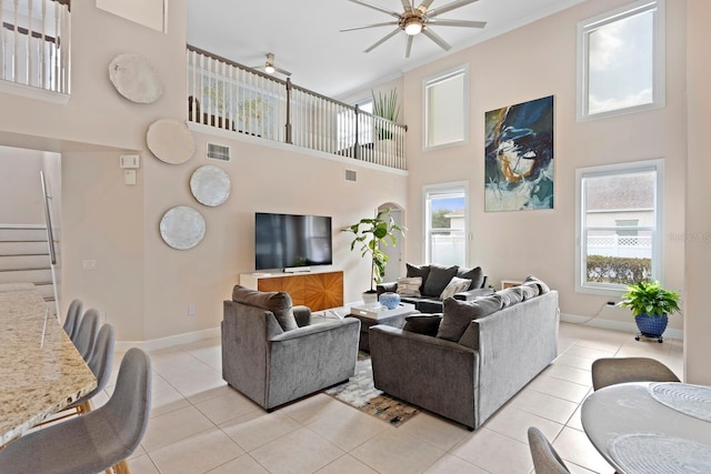 tiled living room featuring crown molding, ceiling fan, and a high ceiling