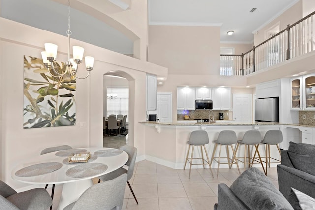 interior space with a high ceiling, crown molding, light tile patterned flooring, and an inviting chandelier