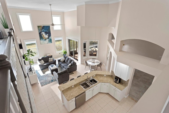 interior space with white cabinetry, hanging light fixtures, light tile patterned floors, light stone counters, and crown molding