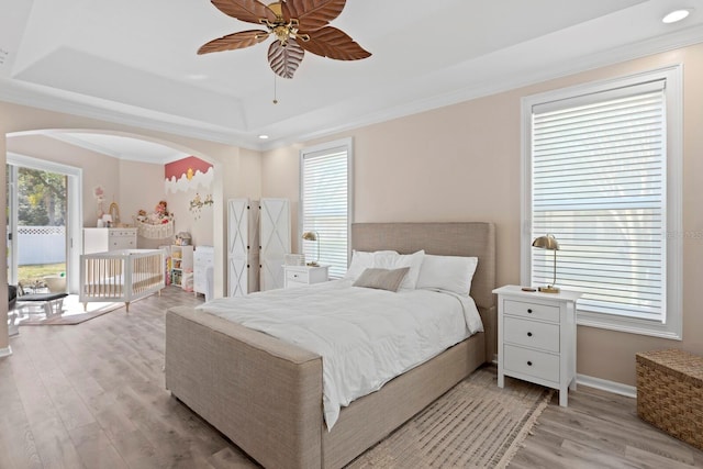 bedroom with a raised ceiling, ornamental molding, access to exterior, and light hardwood / wood-style flooring