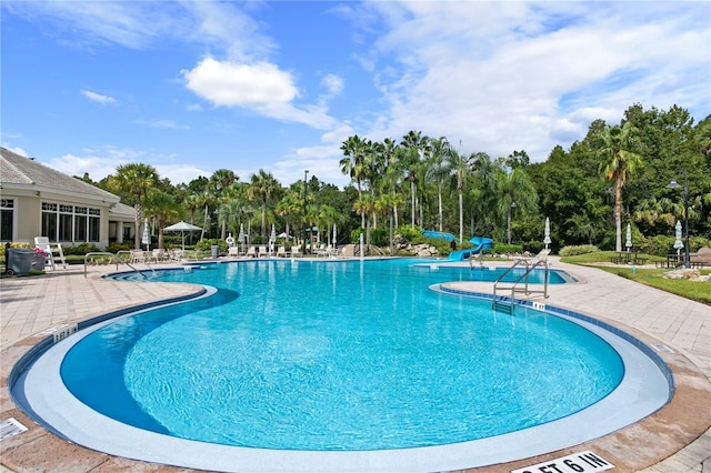 view of swimming pool featuring a water slide and a patio