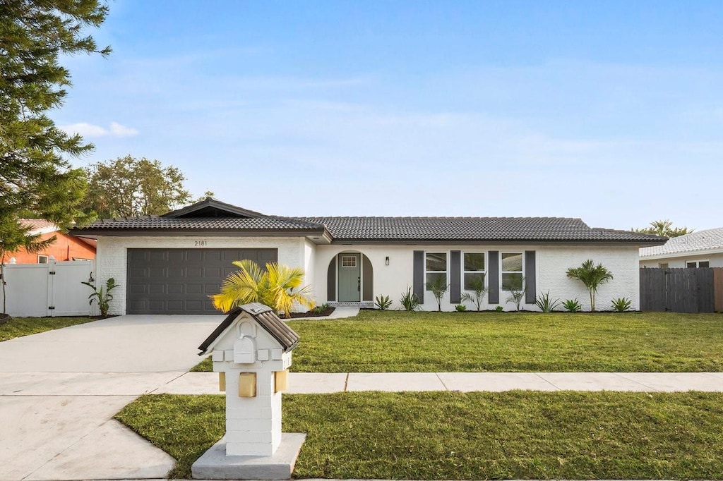 2181 Wateroak Dr N, Clearwater, FL 33764 - ranch-style house featuring fence, concrete driveway, a front lawn, and a garage