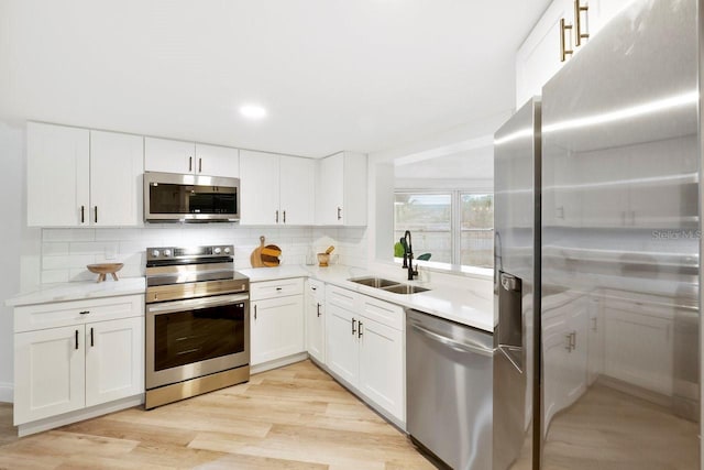 kitchen with white cabinetry, stainless steel appliances, sink, and backsplash