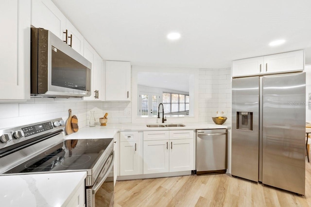 kitchen with white cabinetry, sink, light wood-type flooring, and appliances with stainless steel finishes