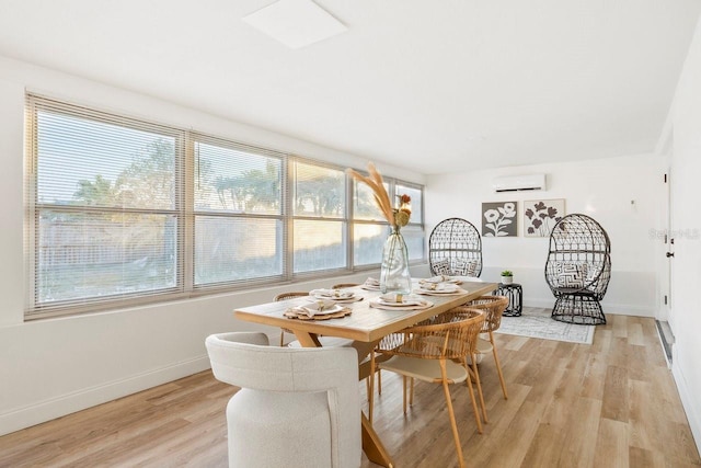 dining room featuring a wall mounted air conditioner and light hardwood / wood-style flooring