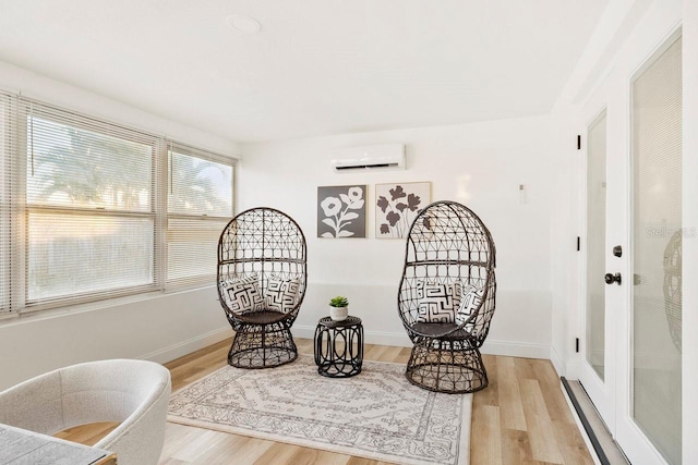 sitting room featuring a wall mounted air conditioner and light hardwood / wood-style flooring