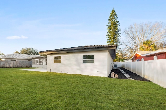 back of house featuring central AC unit, a patio area, and a lawn