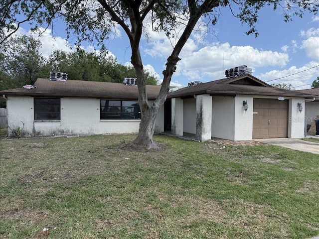 view of front of house with a front yard, driveway, stucco siding, and an attached garage