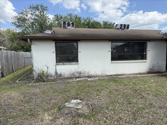view of side of home with stucco siding and fence