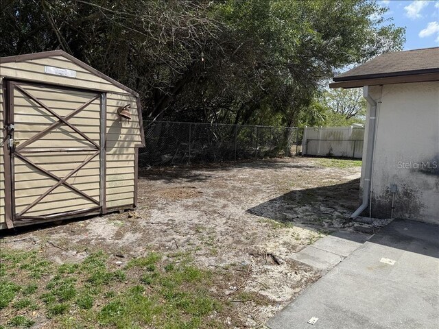 view of yard with a fenced backyard, an outbuilding, and a storage shed