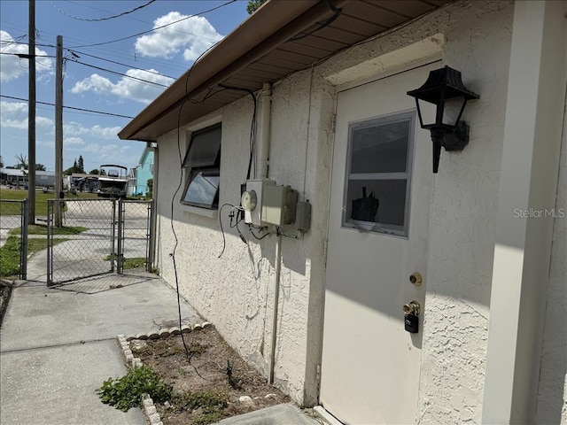 view of side of home featuring stucco siding and a gate