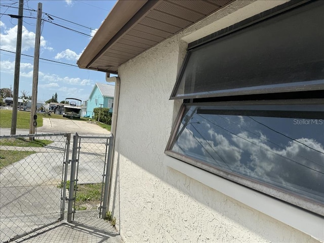 details with stucco siding, a gate, and fence