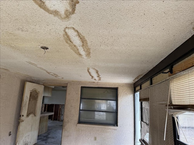 interior space with a textured wall and a textured ceiling