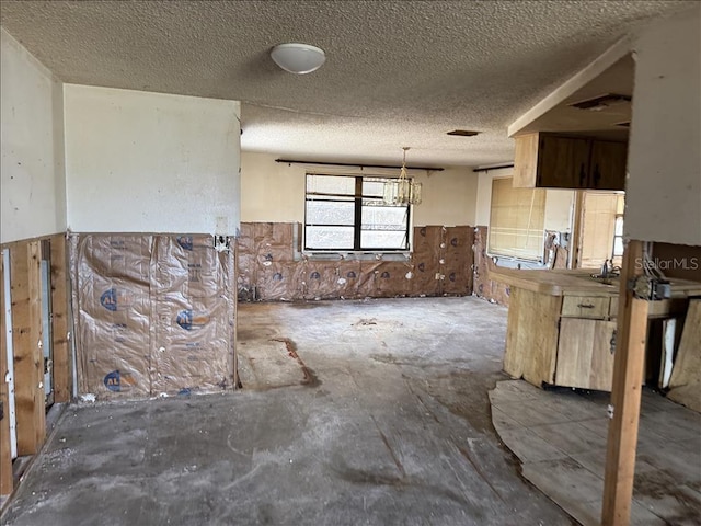 kitchen featuring wainscoting, visible vents, hanging light fixtures, and a textured ceiling