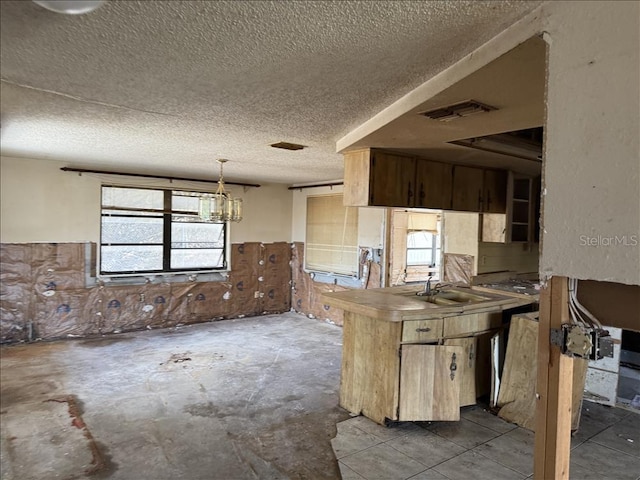 kitchen featuring hanging light fixtures, a sink, a textured ceiling, and visible vents
