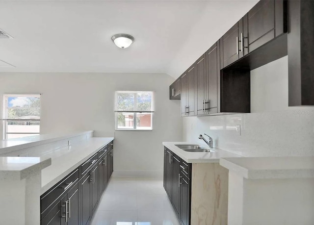 kitchen with sink, tasteful backsplash, vaulted ceiling, light tile patterned floors, and kitchen peninsula