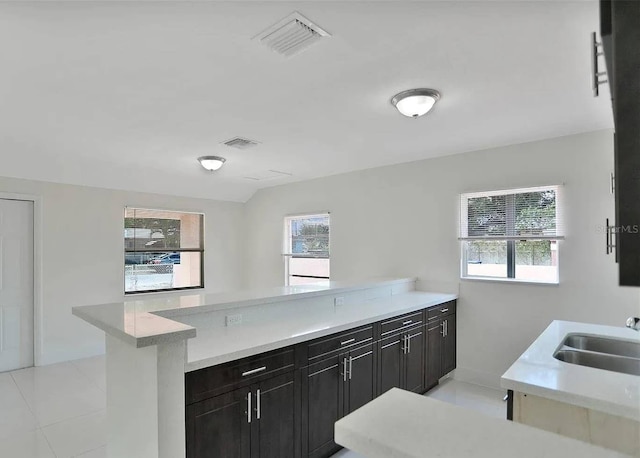 kitchen featuring sink, light tile patterned floors, kitchen peninsula, and a healthy amount of sunlight