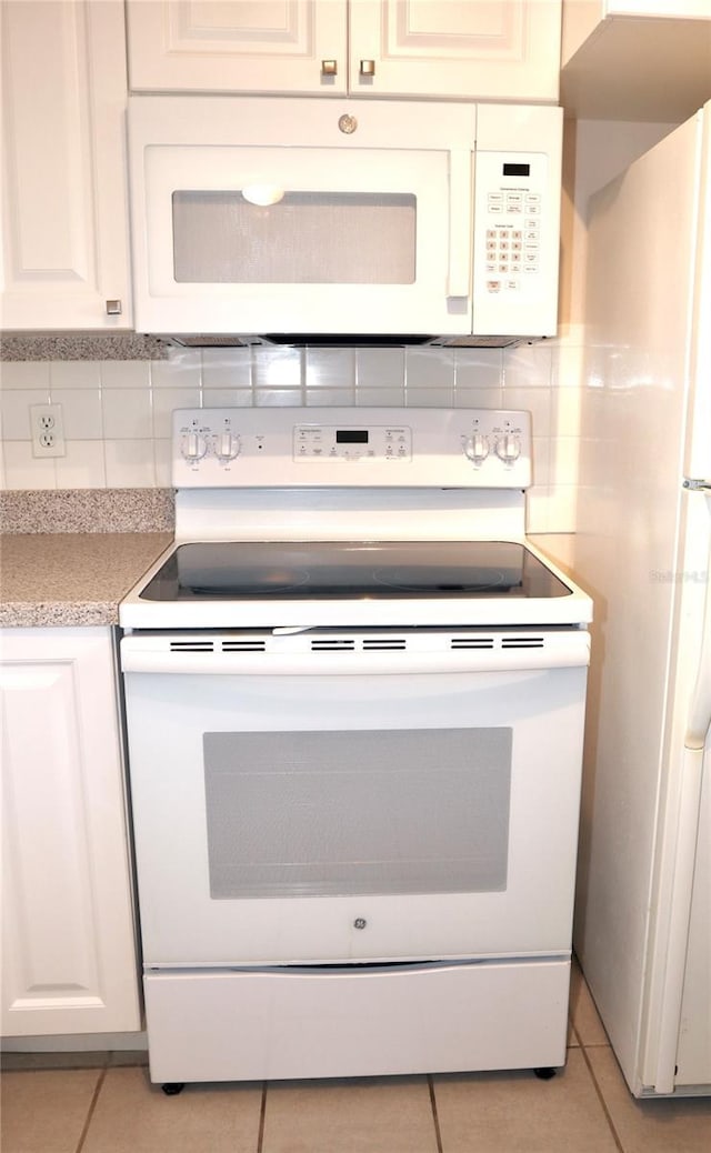 kitchen featuring white cabinetry, light tile patterned flooring, backsplash, and white appliances