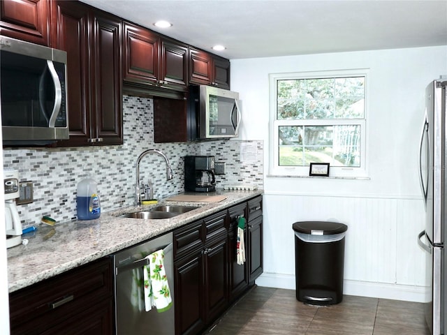 kitchen featuring tasteful backsplash, sink, light stone counters, and appliances with stainless steel finishes