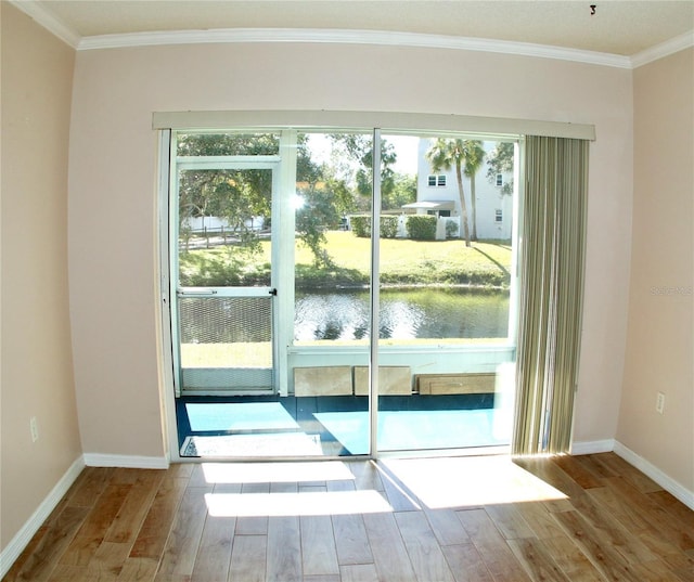 doorway with crown molding, a wealth of natural light, light hardwood / wood-style floors, and a water view