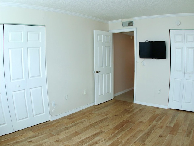 unfurnished bedroom featuring ornamental molding, light hardwood / wood-style flooring, and a textured ceiling