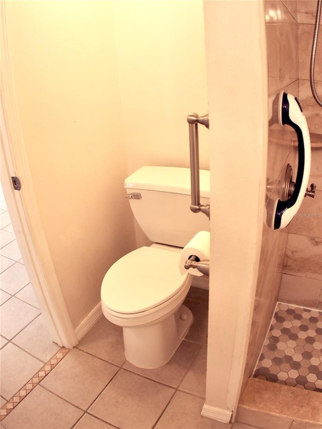 bathroom featuring toilet, tile patterned flooring, and a tile shower