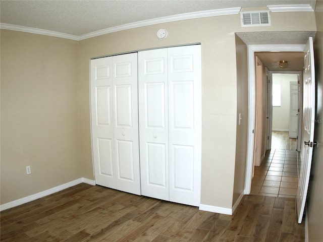 unfurnished bedroom featuring ornamental molding, dark hardwood / wood-style floors, and a closet