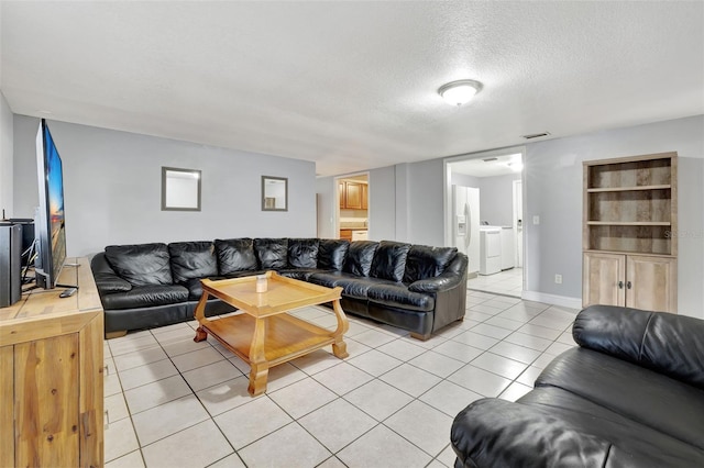 living room with washer and dryer, a textured ceiling, and light tile patterned flooring