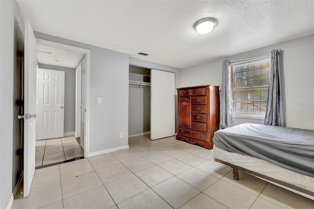 bedroom featuring light tile patterned floors, a textured ceiling, and a closet