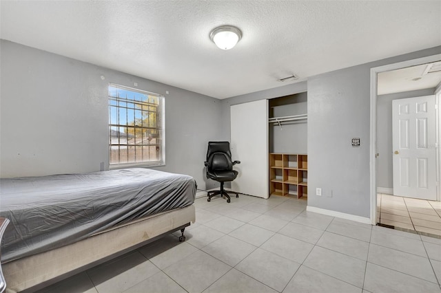 tiled bedroom featuring a closet and a textured ceiling