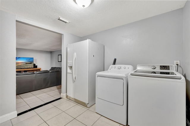 laundry area featuring a textured ceiling, washer and dryer, and light tile patterned floors