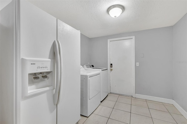 laundry area featuring light tile patterned flooring, washing machine and clothes dryer, and a textured ceiling