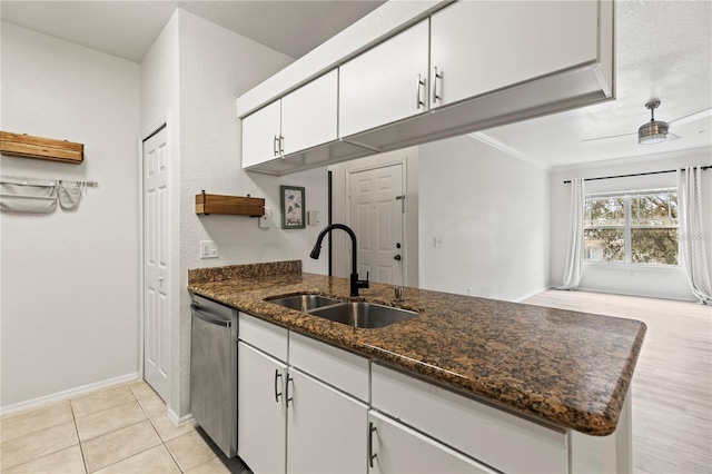 kitchen with sink, white cabinetry, ornamental molding, stainless steel dishwasher, and dark stone counters