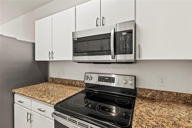 kitchen with dark stone countertops, appliances with stainless steel finishes, and white cabinets