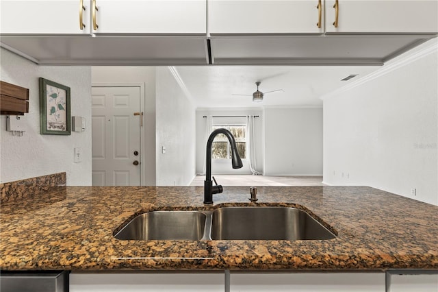 kitchen with sink, ceiling fan, dark stone countertops, ornamental molding, and white cabinets