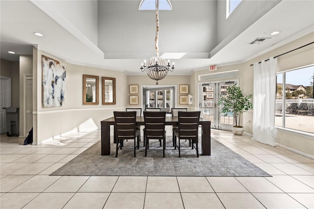 tiled dining area featuring french doors, a towering ceiling, ornamental molding, and a chandelier