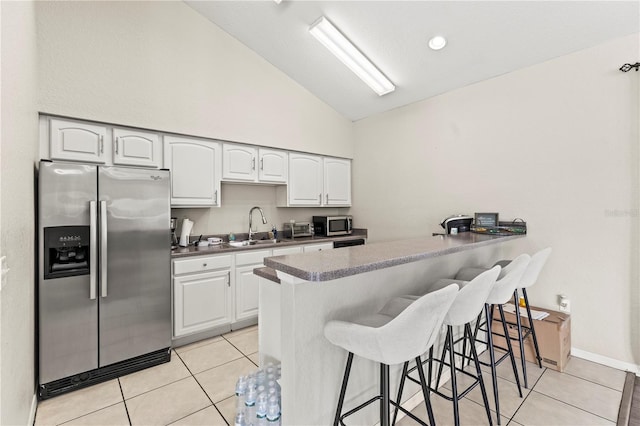 kitchen with a breakfast bar, sink, white cabinetry, appliances with stainless steel finishes, and kitchen peninsula