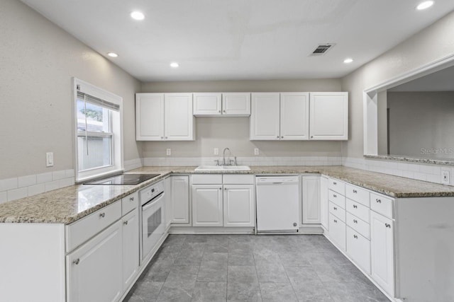 kitchen featuring sink, kitchen peninsula, white appliances, light stone countertops, and white cabinets