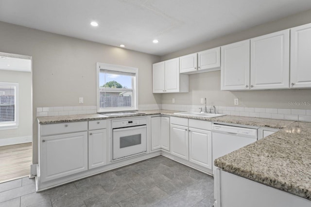 kitchen with white cabinetry, sink, light stone counters, and white appliances