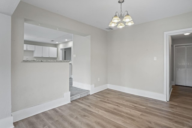 unfurnished dining area featuring a notable chandelier and light hardwood / wood-style floors