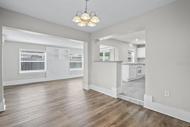 unfurnished living room with wood-type flooring and a notable chandelier