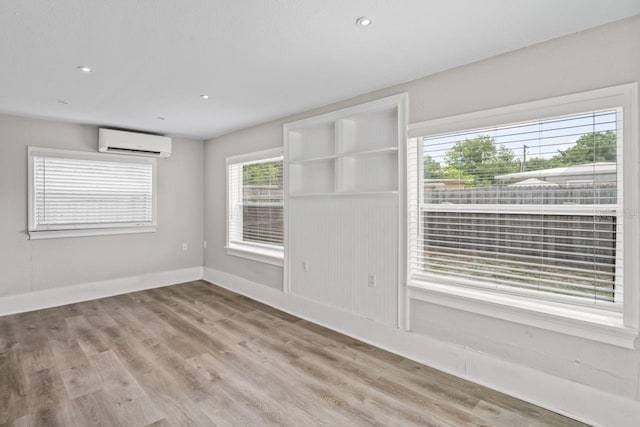 spare room featuring a wall mounted AC and light hardwood / wood-style flooring