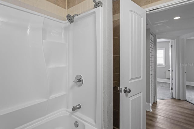 bathroom featuring hardwood / wood-style flooring and washtub / shower combination