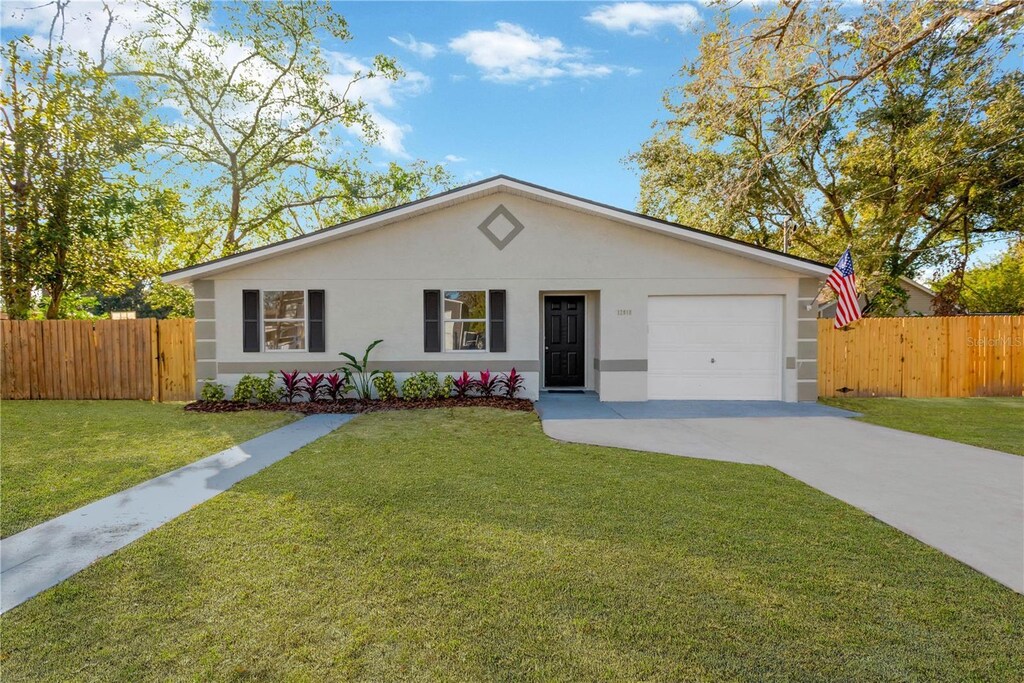12918 Cambridge Ave, Tampa, FL 33624 - ranch-style home with driveway, a garage, and stucco siding