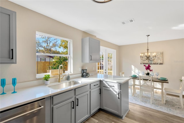 kitchen with sink, gray cabinets, dishwasher, light hardwood / wood-style floors, and kitchen peninsula