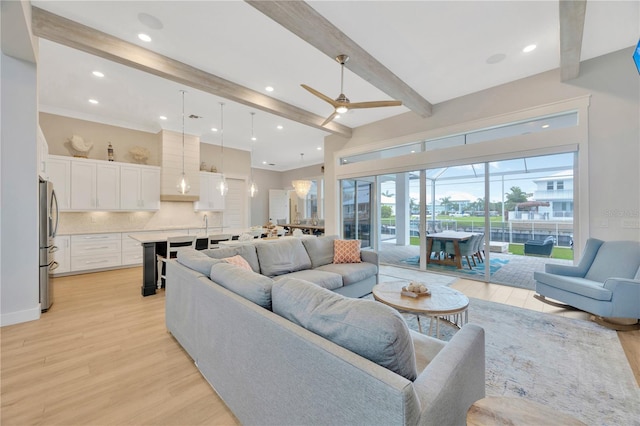 living room with beam ceiling, ceiling fan, and light wood-type flooring