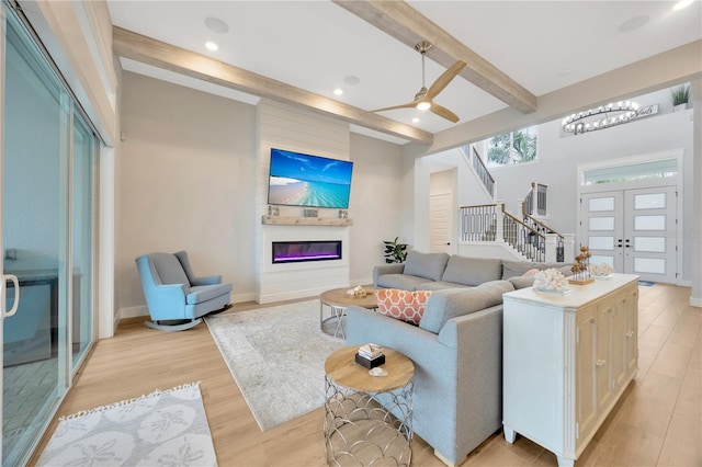 living room featuring ceiling fan, french doors, beamed ceiling, and light wood-type flooring