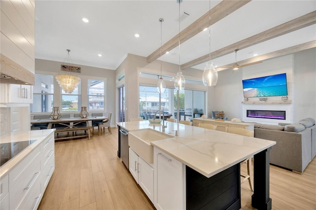 kitchen featuring white cabinetry, decorative light fixtures, sink, and a spacious island