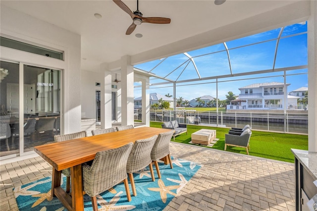 sunroom featuring ceiling fan and a water view